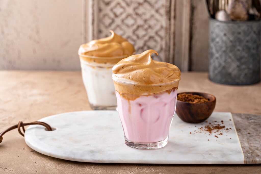 Dalgona whipped coffee with iced strawberry milk in a glass, trendy coffee drink
