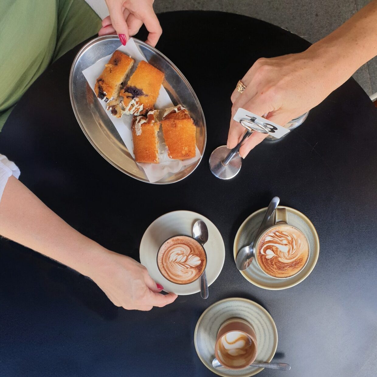 female hands holding coffee cup and food on table at cafe
