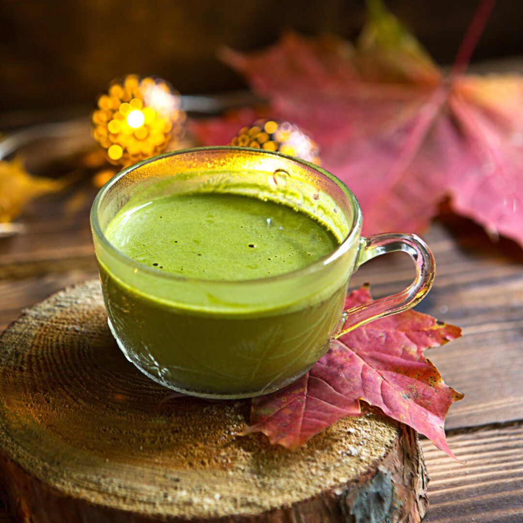 Green Japanese matcha tea with foam in transparent Cup on wooden table in autumn