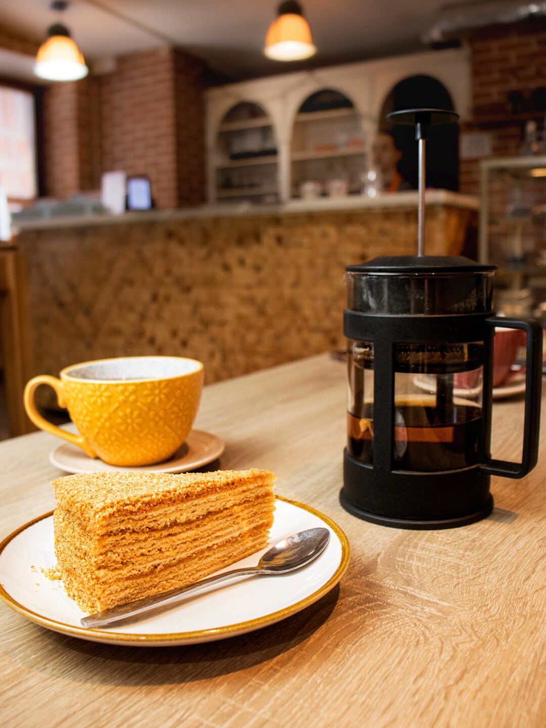 piece of Napoleon cake and tea in a teapot and a cup on a table in a cafe, breakfast in a cafe