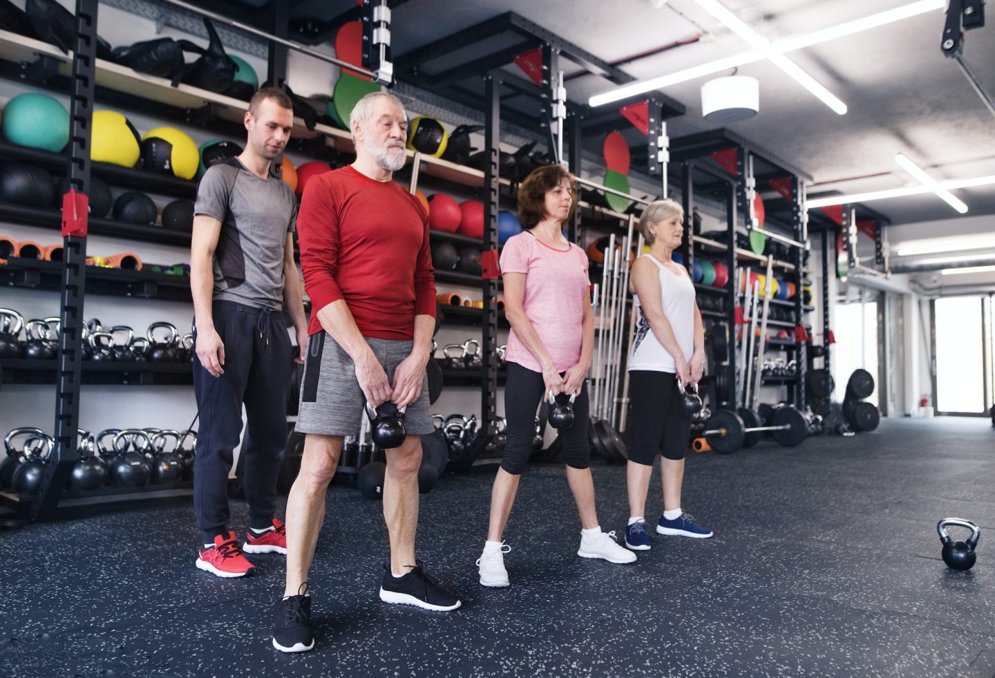 Group of fit seniors with personal trainer in gym