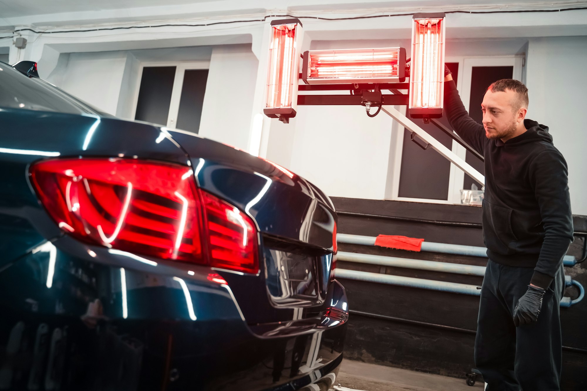 Detailing worker with infrared lamps near the car. Car detailing concept