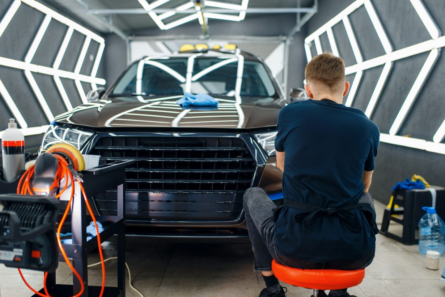 Male worker polishes car surface, detailing