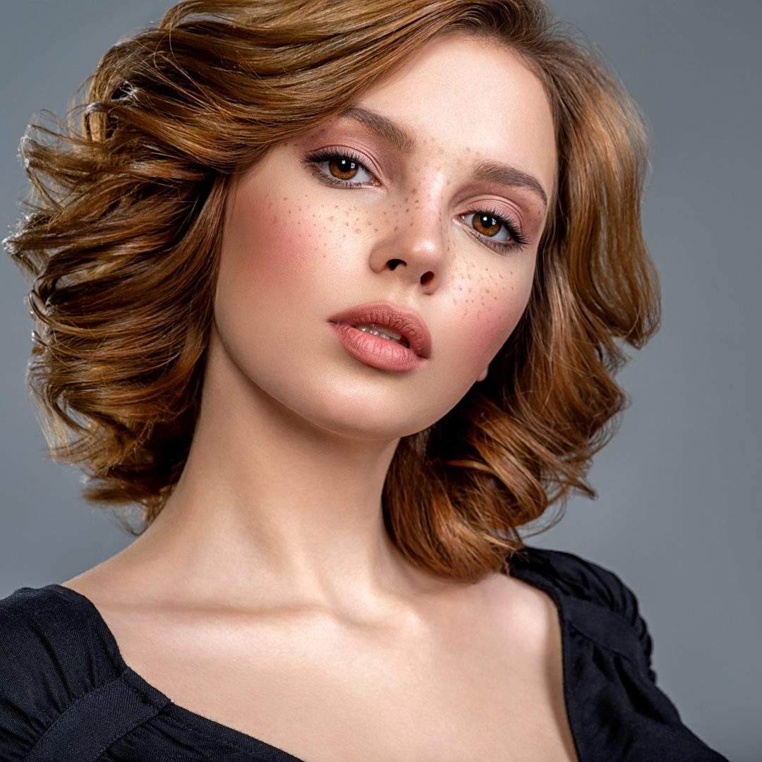 Woman with a curly hair. Beautiful young woman with freckles on face.