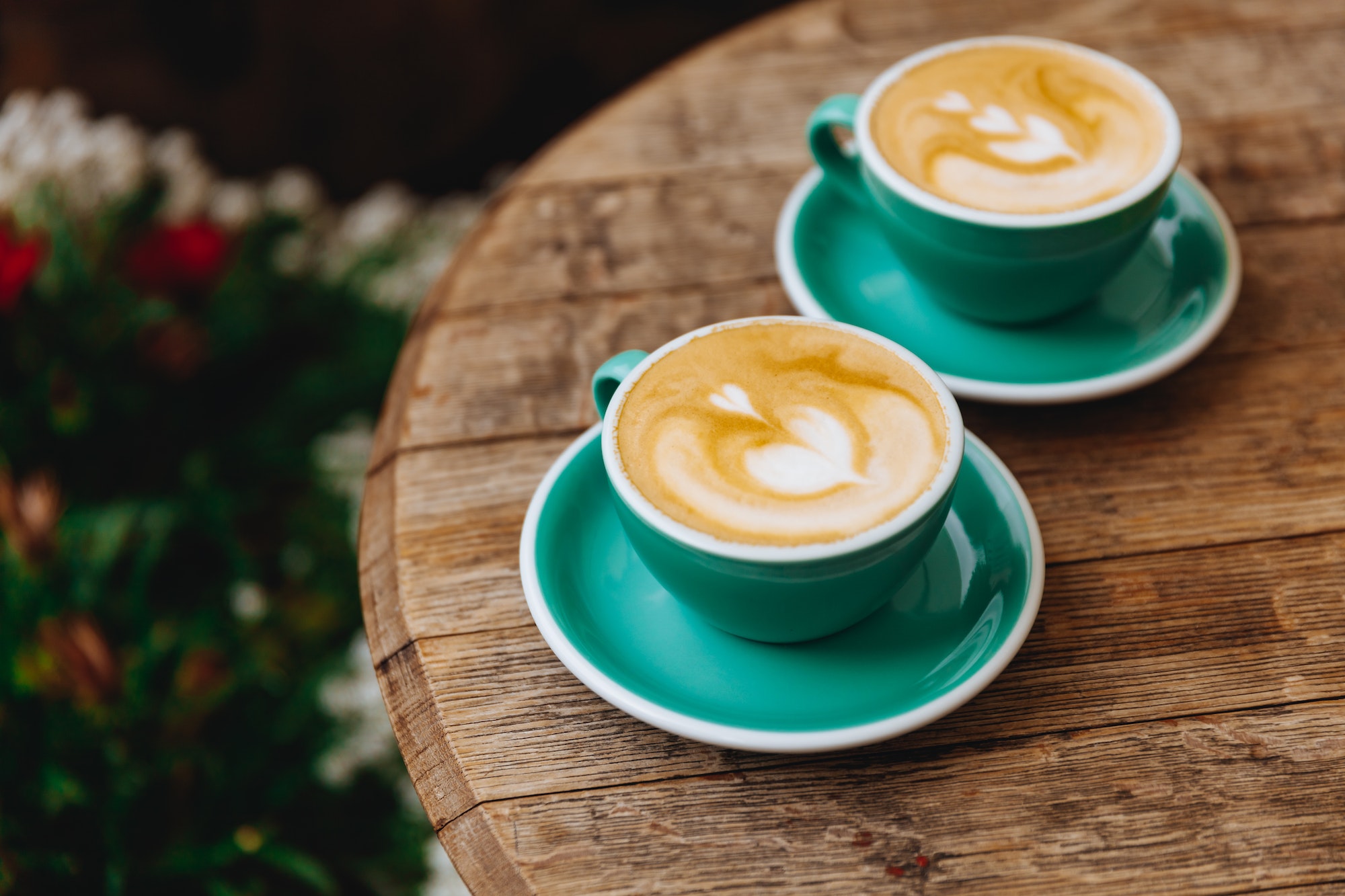 Freshly brewed coffee in two turquoise colored mugs at cafe