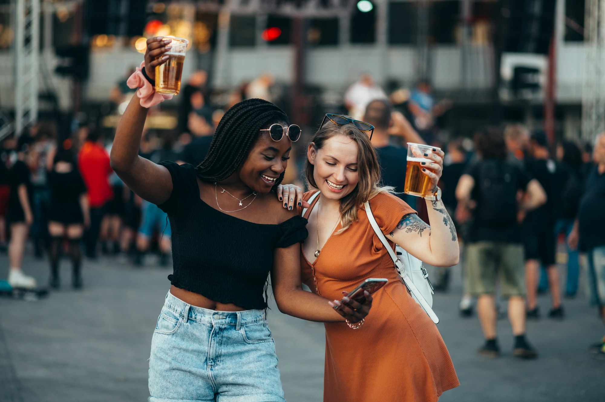 Friends using smartphone and drinking beer on a music festival