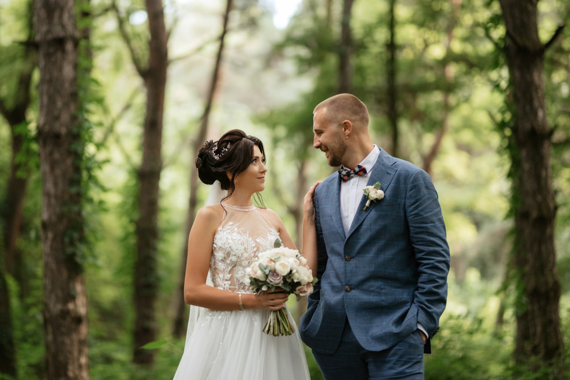 wedding walk of the bride and groom in the deciduous forest in summer