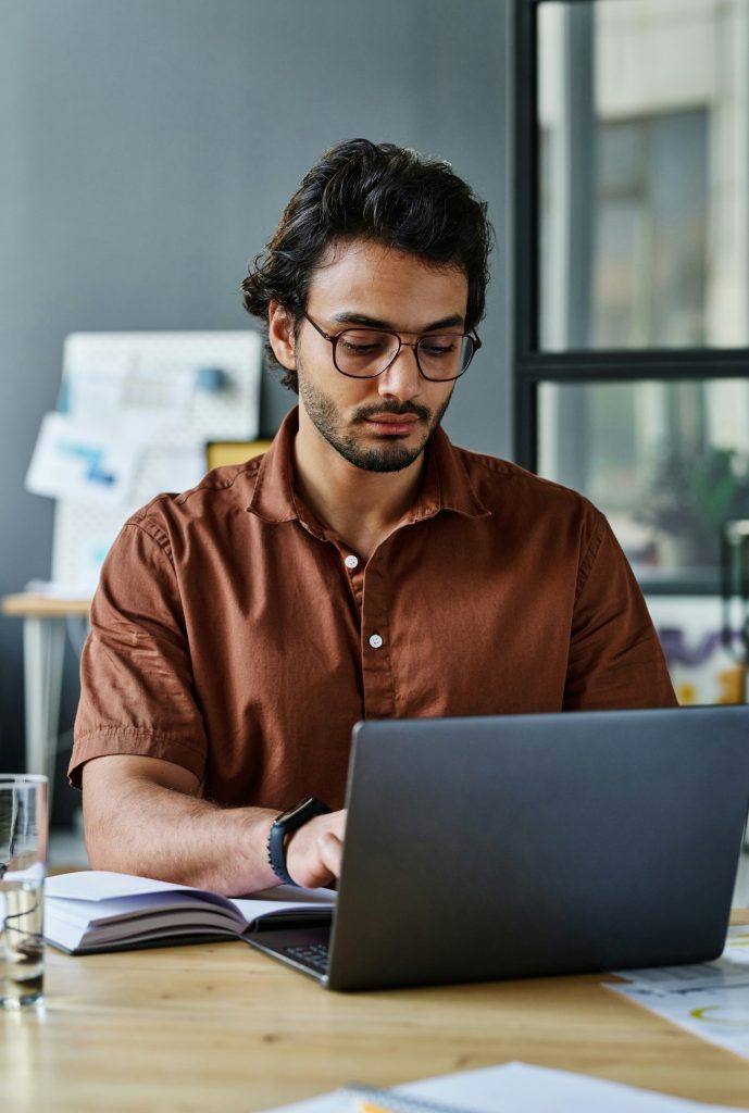 Young serious manager or designer networking by desk