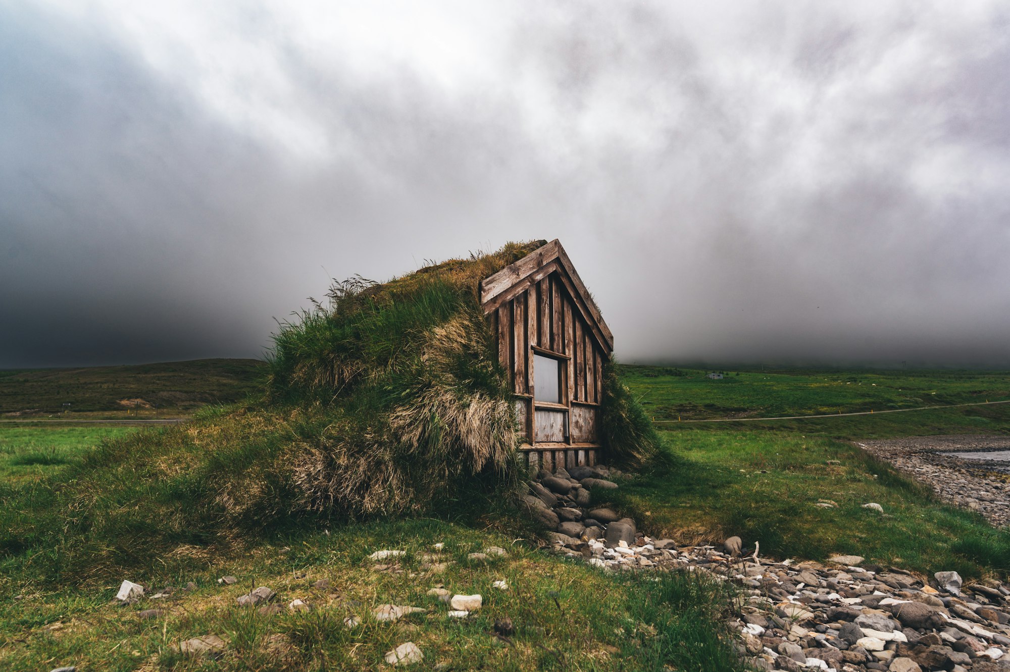 An abandoned cottage in wild nature with a dramatic sky.