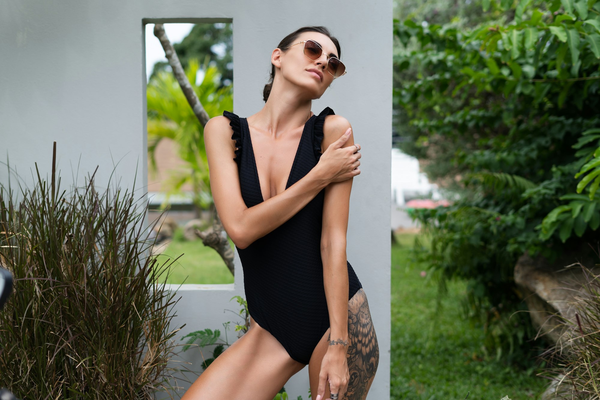Beautiful european woman in black swimsuit posing outside at villa