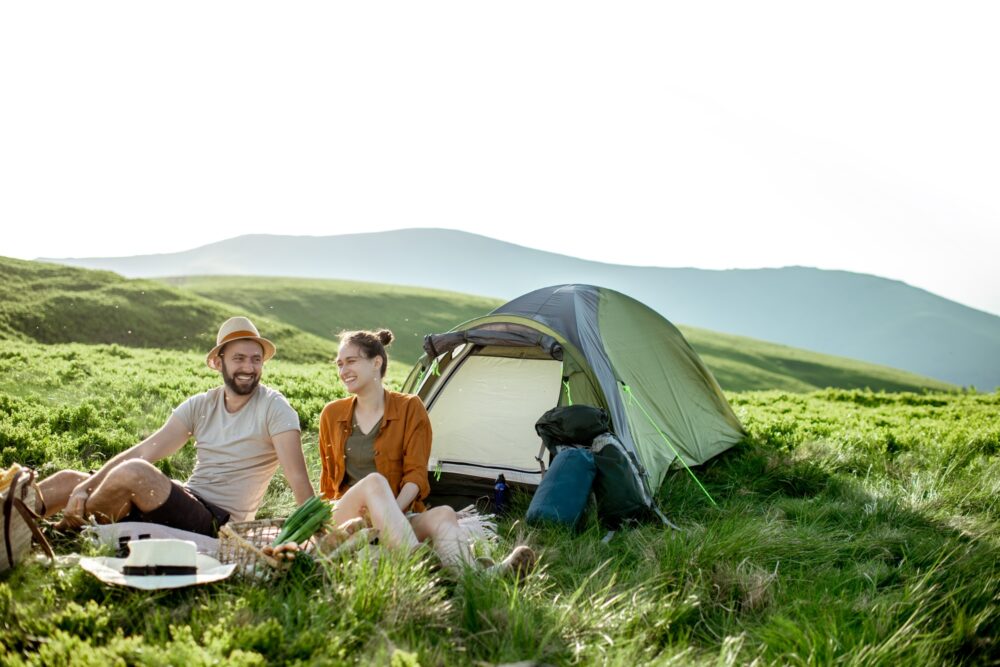 Couple having a picnic near the tent in the mountains
