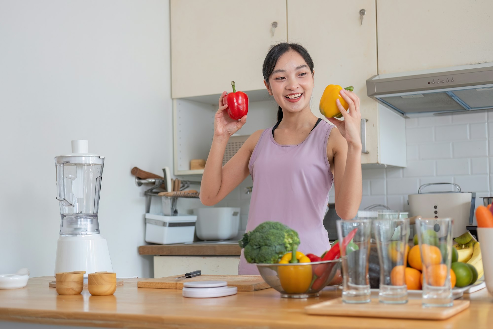 happy young woman cooking healthy vegetarian food at home. Fit smiling housewife or fitness coach in
