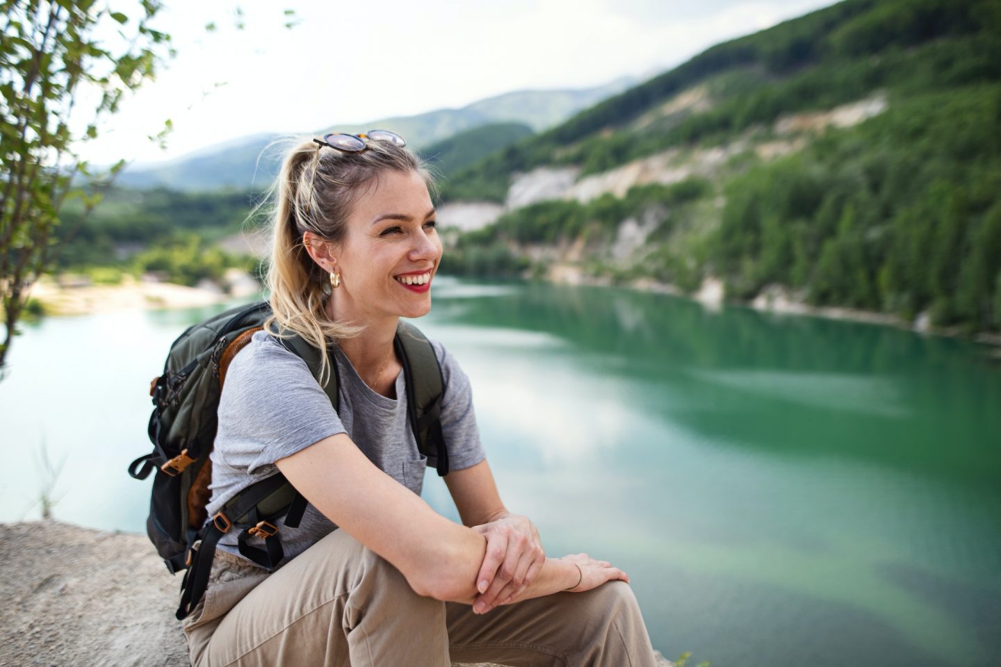 Mid adult woman tourist on hiking trip on summer holiday, resting by lake