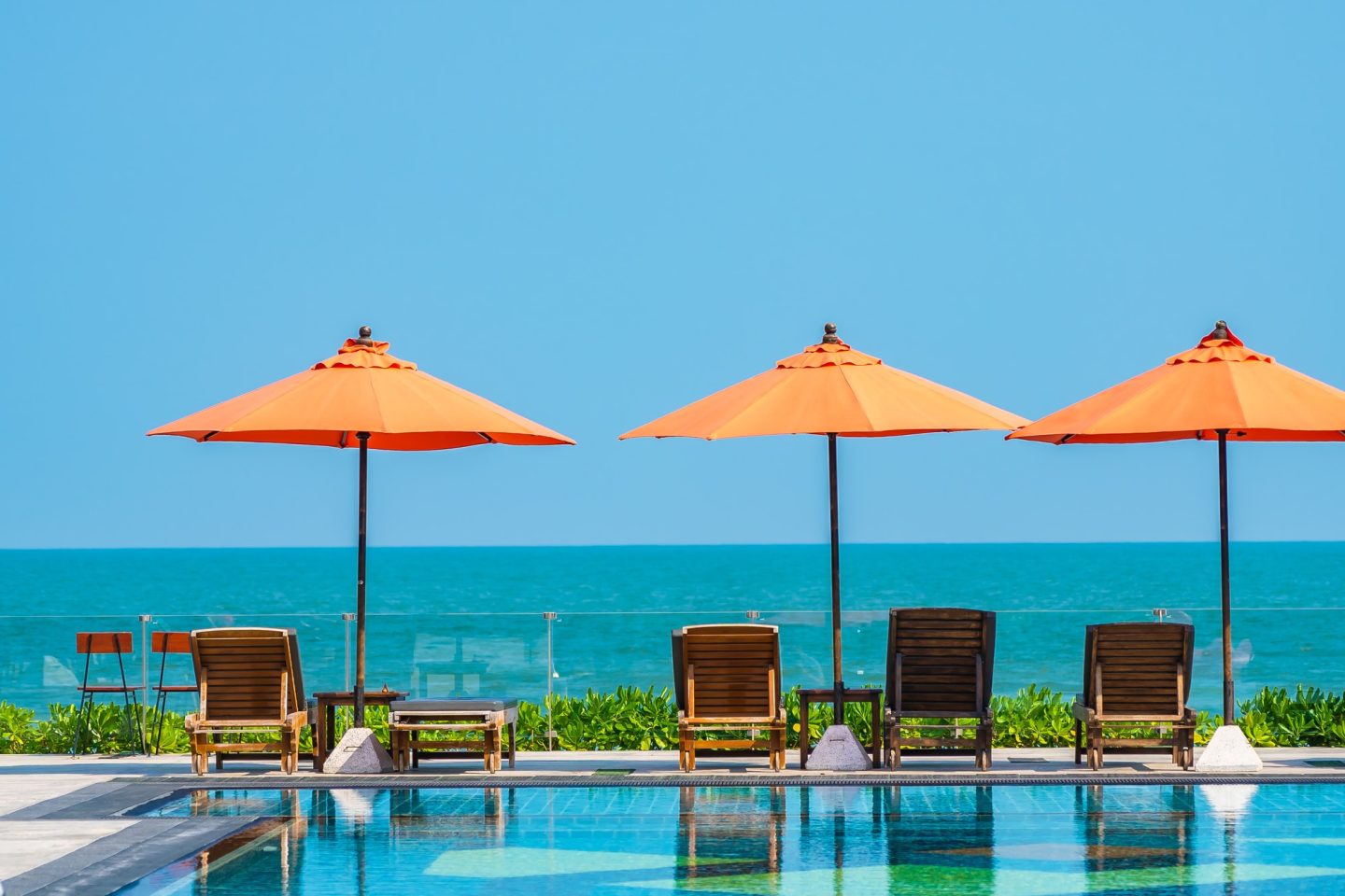 Umbrella and chair around outdoor swimming pool neary sea in hotel resort