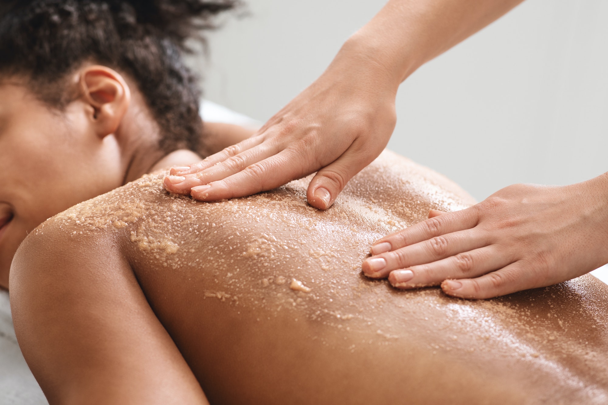 African american lady having skin scrubbing procedure at spa salon