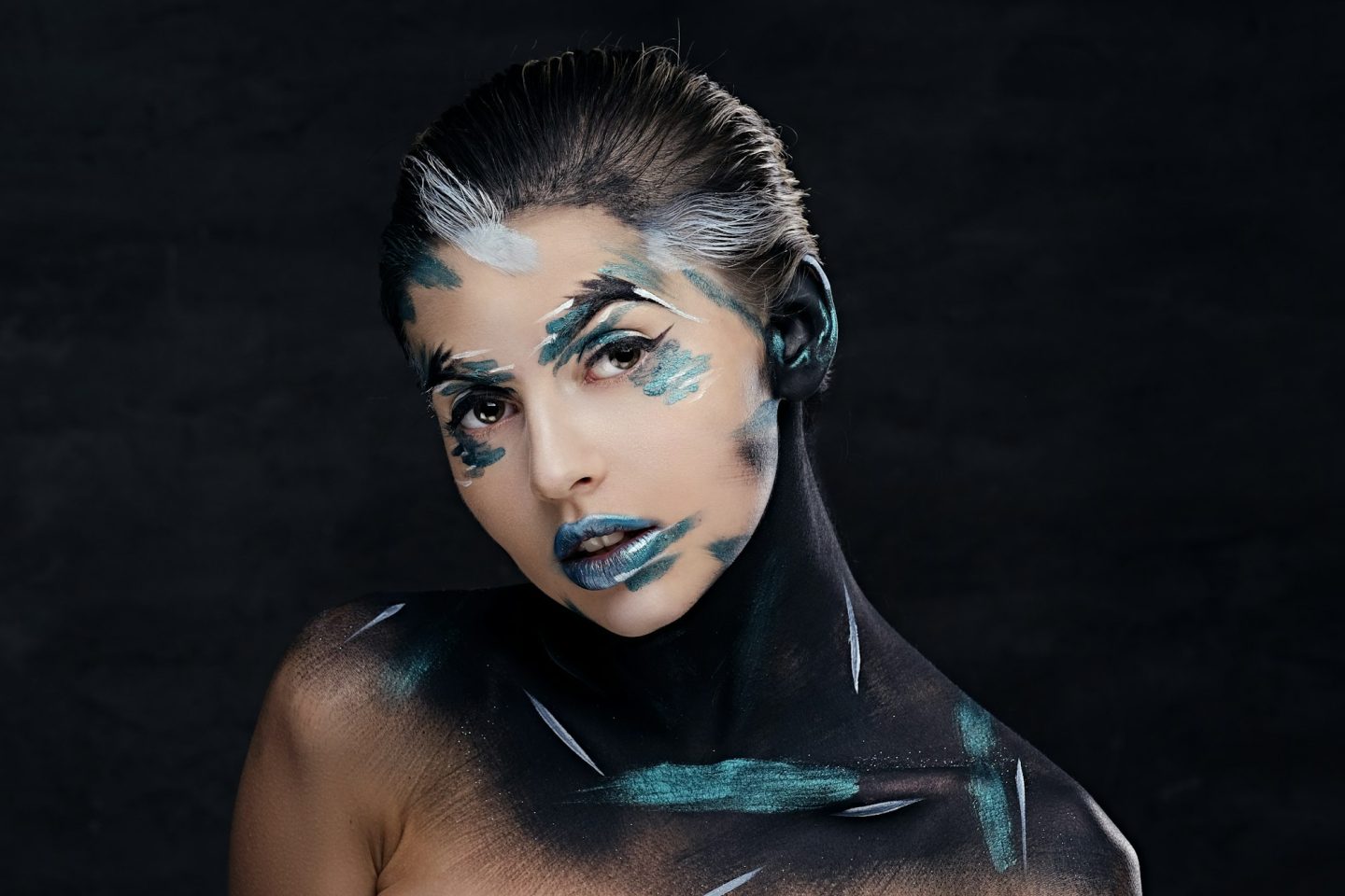 A woman with colorful make up and painted art on a neck.