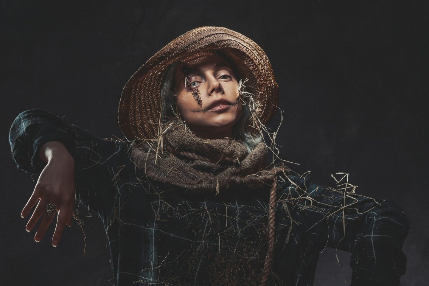 Awful scarecrow posing in dark background with hat