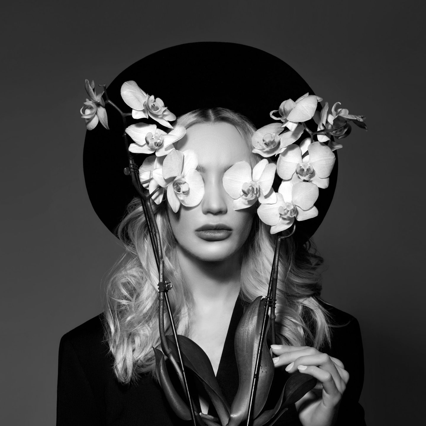 Portrait of a Blonde woman in a large round black hat, an Orchid flower in her hands