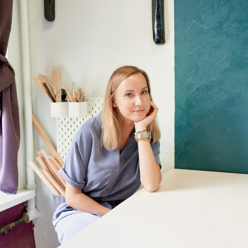 Business woman sitting at table and smiling in ceramic workshop. Young businesswoman at pottery