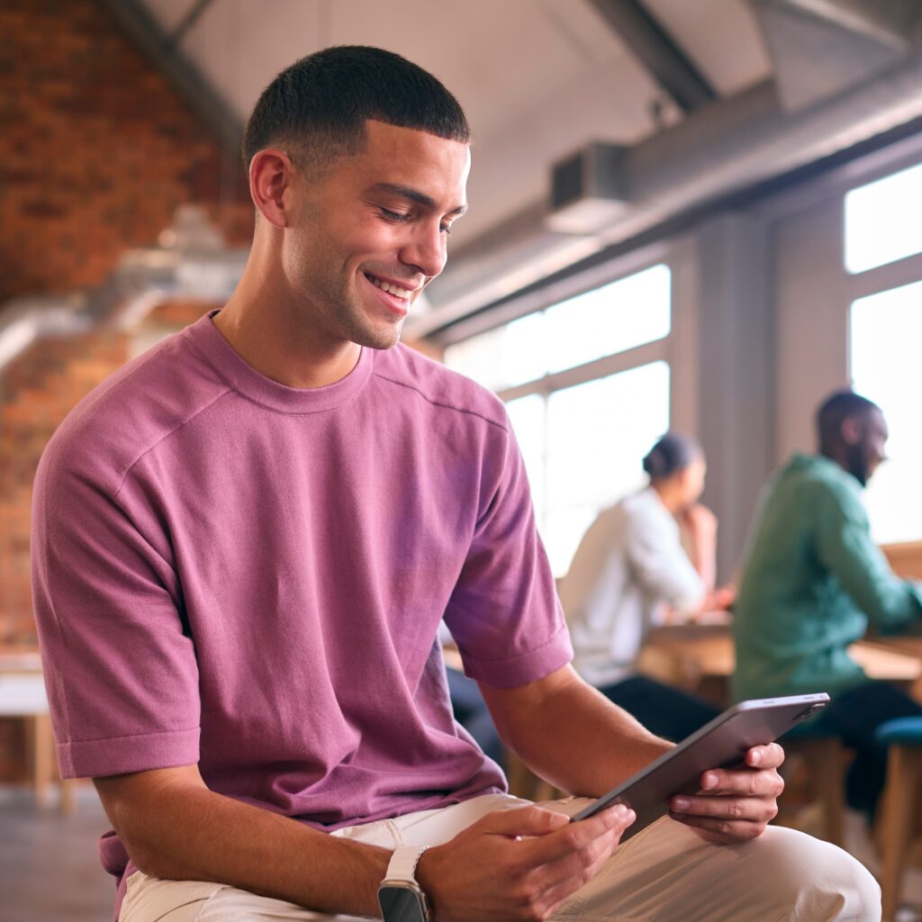 Young Businessman Using Digital Tablet Working In Modern Open Plan Office