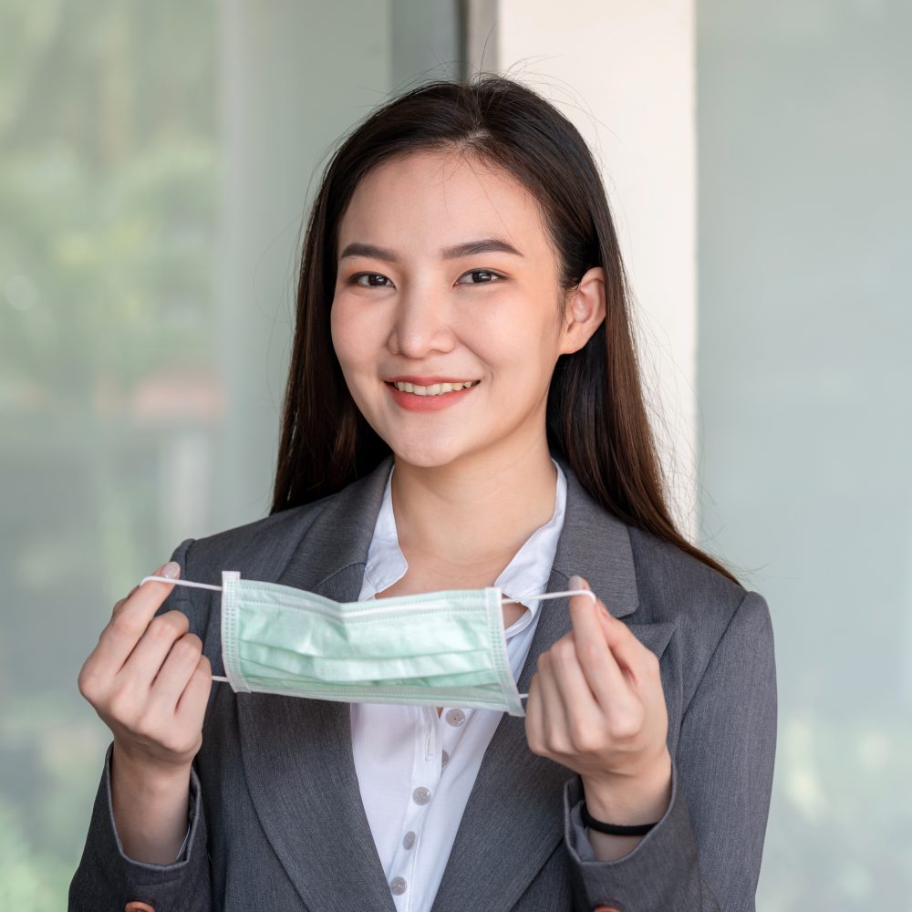 Asian businesswoman in suit, preparing to wearing protective face mask to protection from covid-19