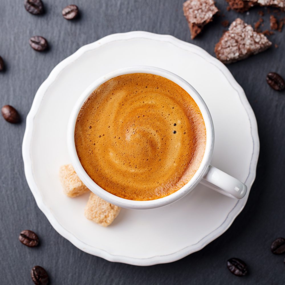 Coffee Espresso in White Cup on Black Slate Background. Top View.