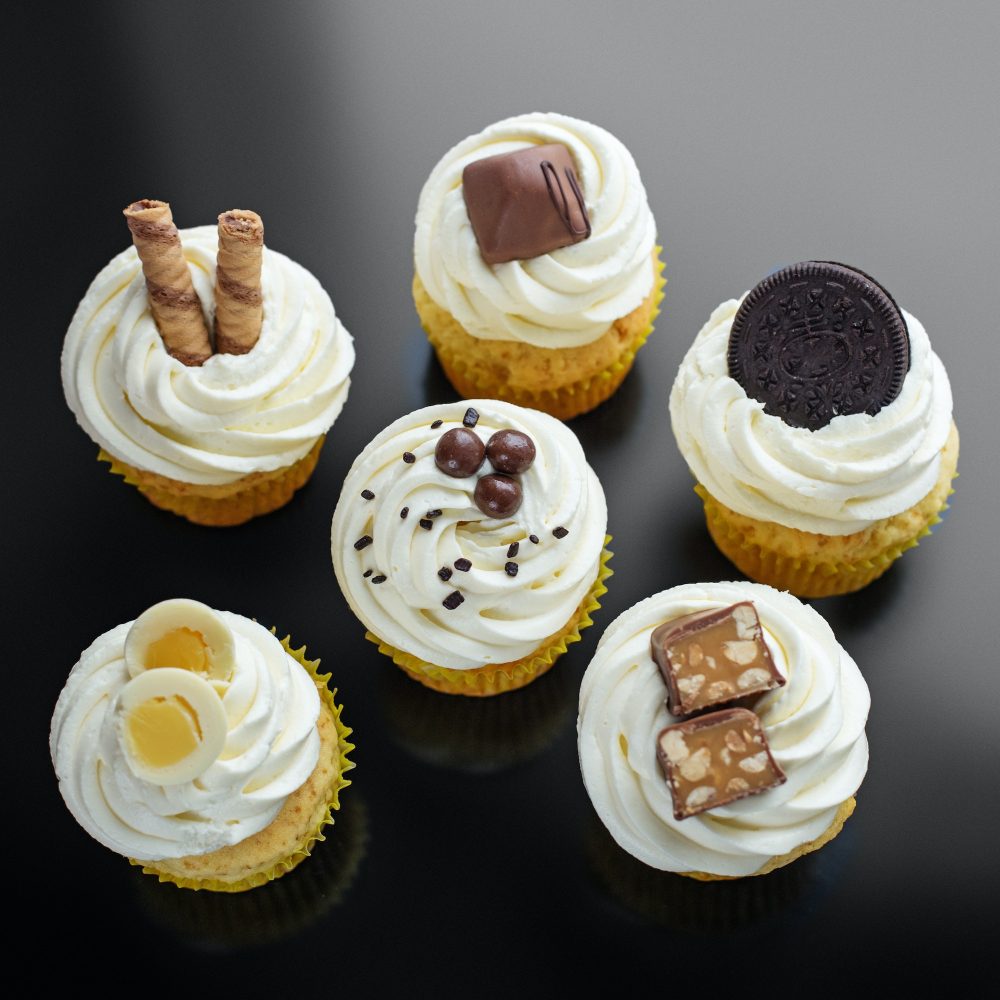 Delicious cupcakes with delicate cream and sweets on a black background. Concept for food
