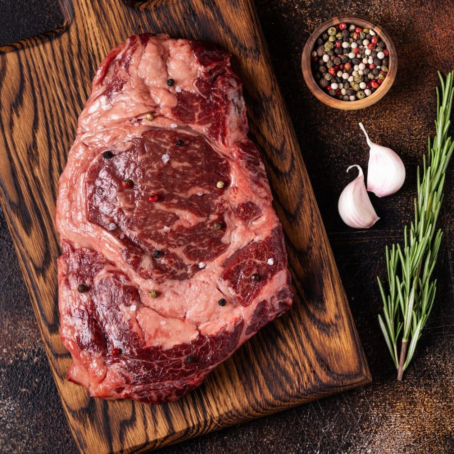 Fresh raw beef steak on a cutting wooden board.