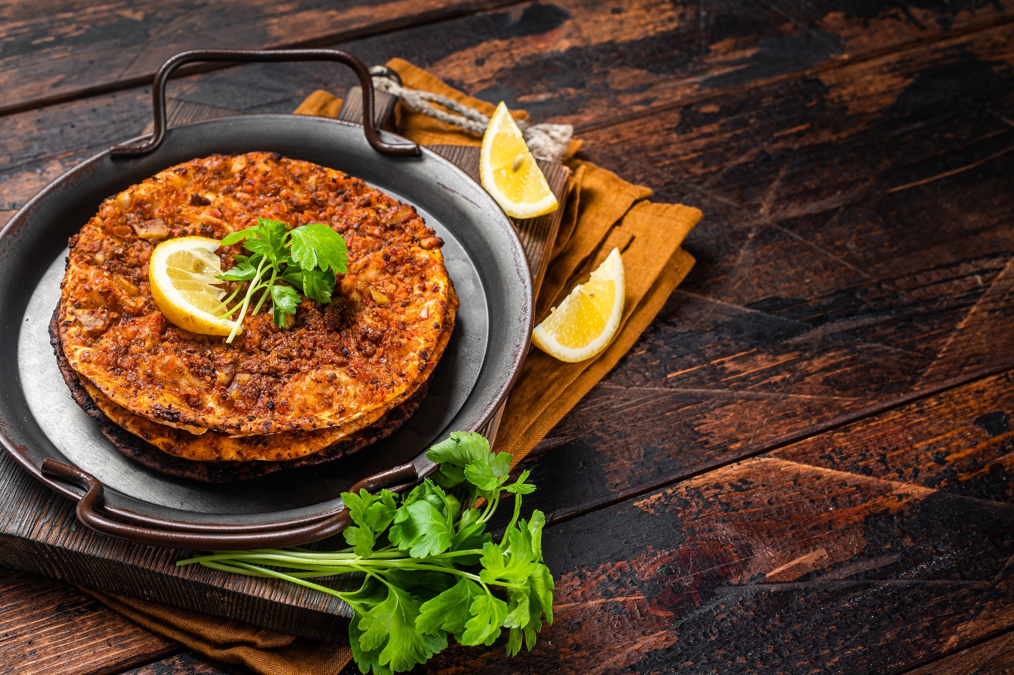 Traditional delicious Turkish foods lahmacun with mince lamb meat in steel tray. Wooden background