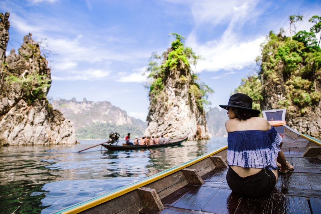 A beautiful asian woman traveling by long tail boat in the ocean or lake.