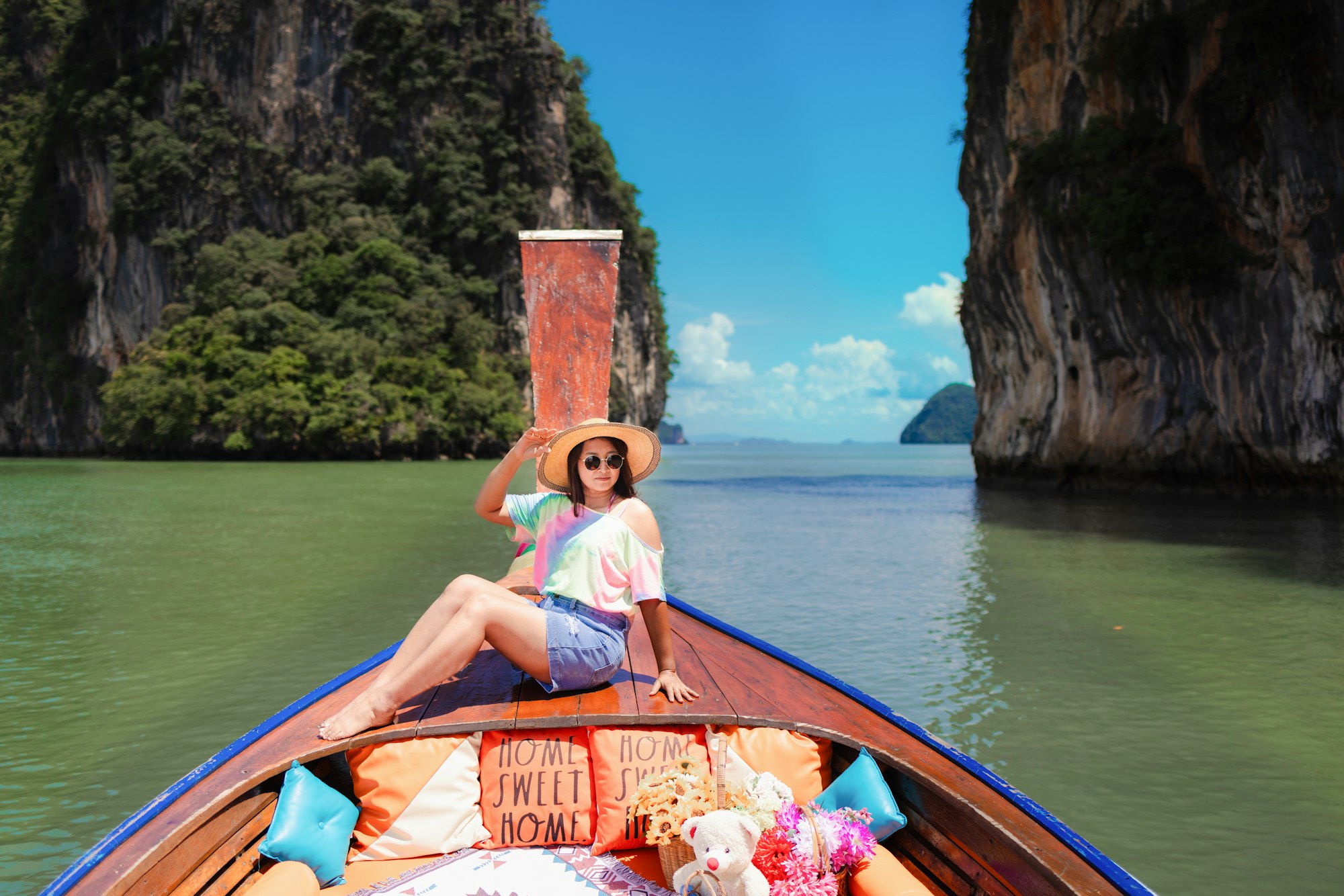Traveler woman in summer dress relaxing on wooden boat joy view of Phang Nga bay, near Phuket