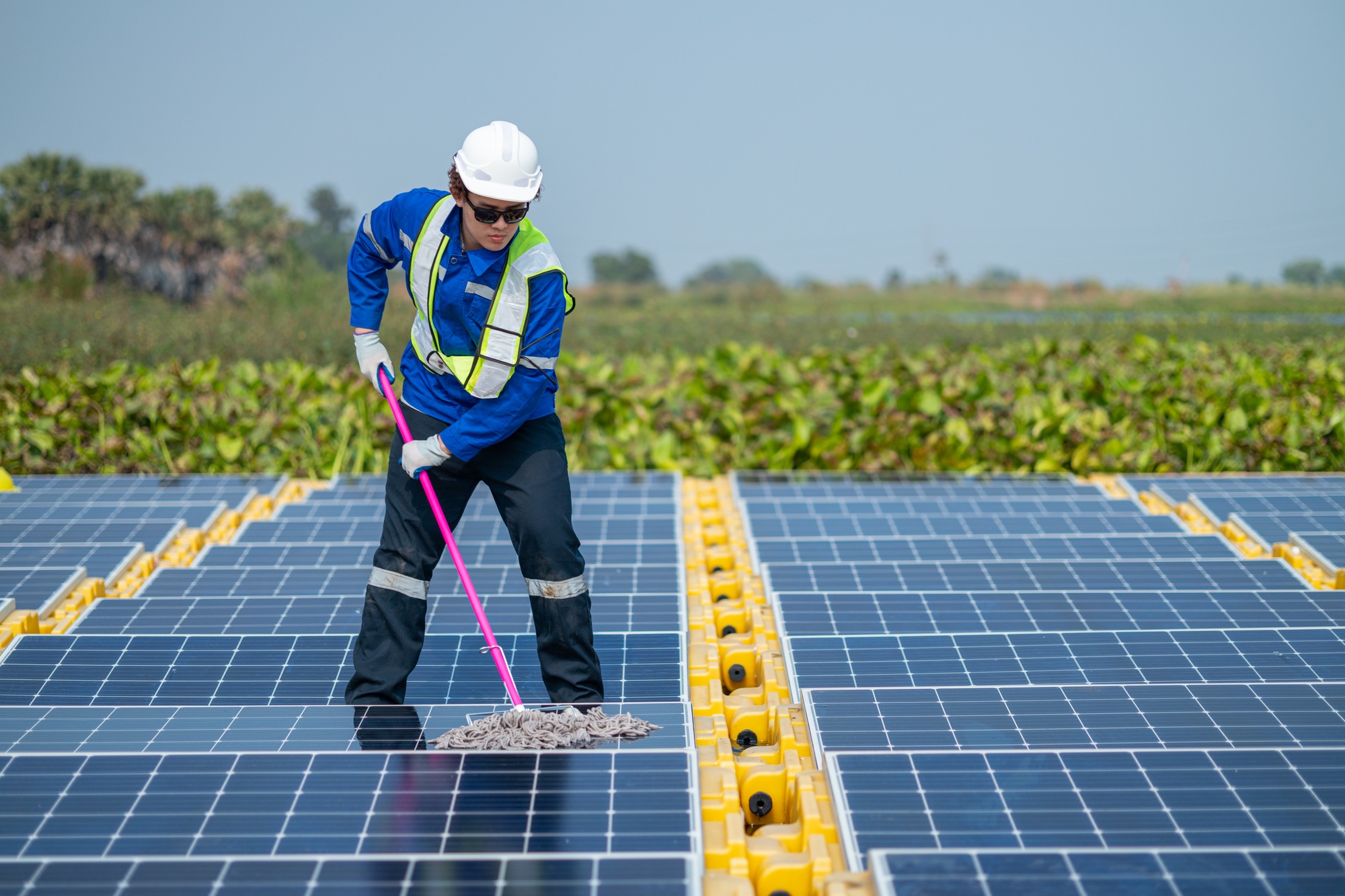 Worker Cleaning Solar Panels at Renewable Energy Farm