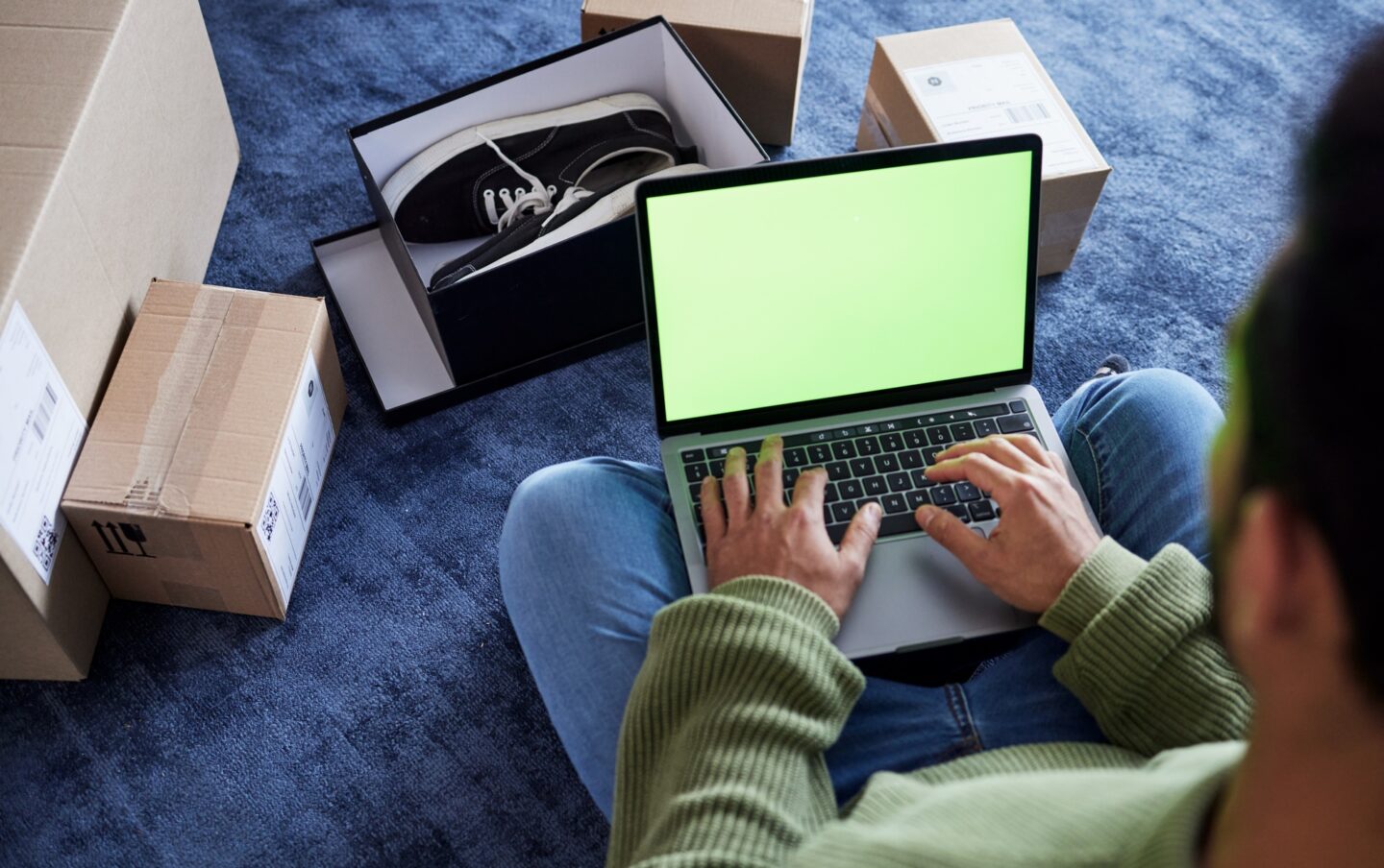 Ecommerce, man with laptop, green screen and boxes on floor, shoes and delivery service on digital