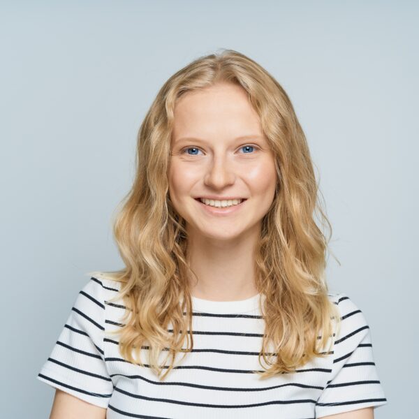 Beautiful young smiling blonde woman without makeup on white wall